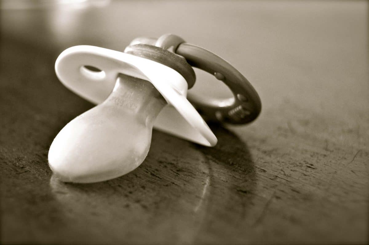 A black and white photo of a pacifier on a table