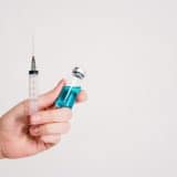 A personal holding a needle and vial of vaccine.