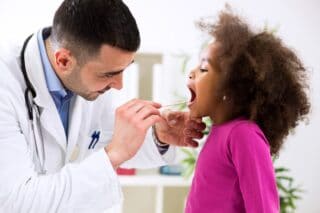 Doctor examining a child sick with a soar throat