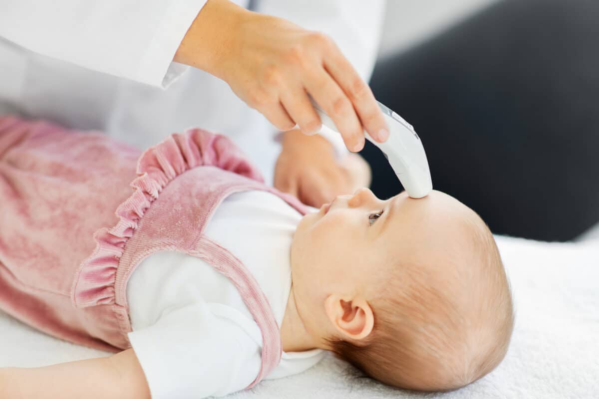 doctor taking baby's temperature with forehead thermometer