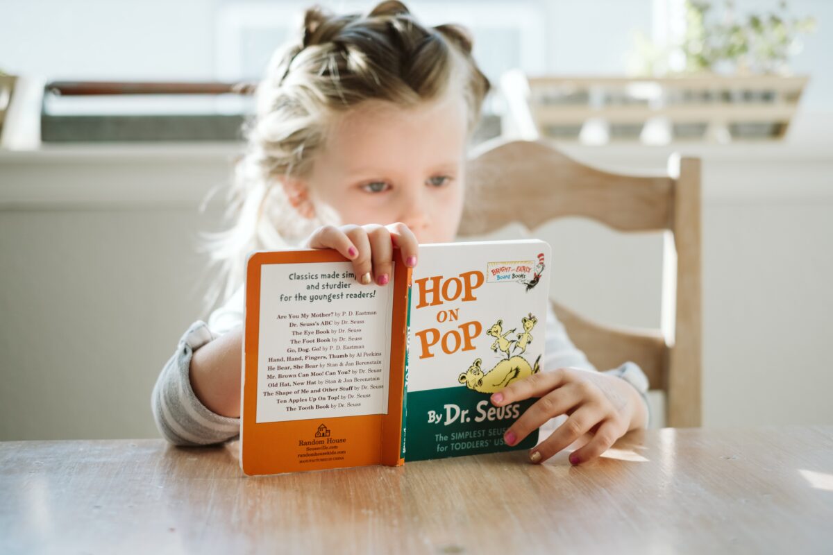 little girl reading board book