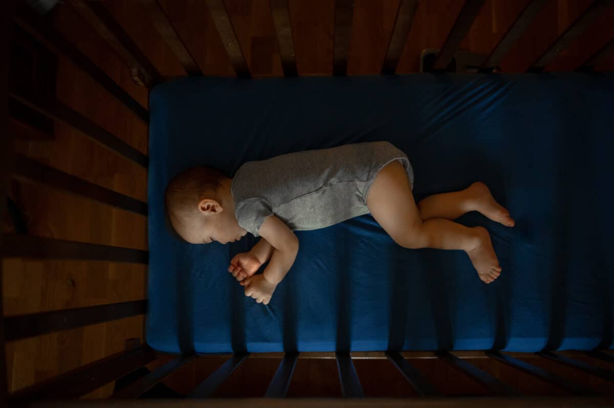 baby asleep in crib in a darkened room