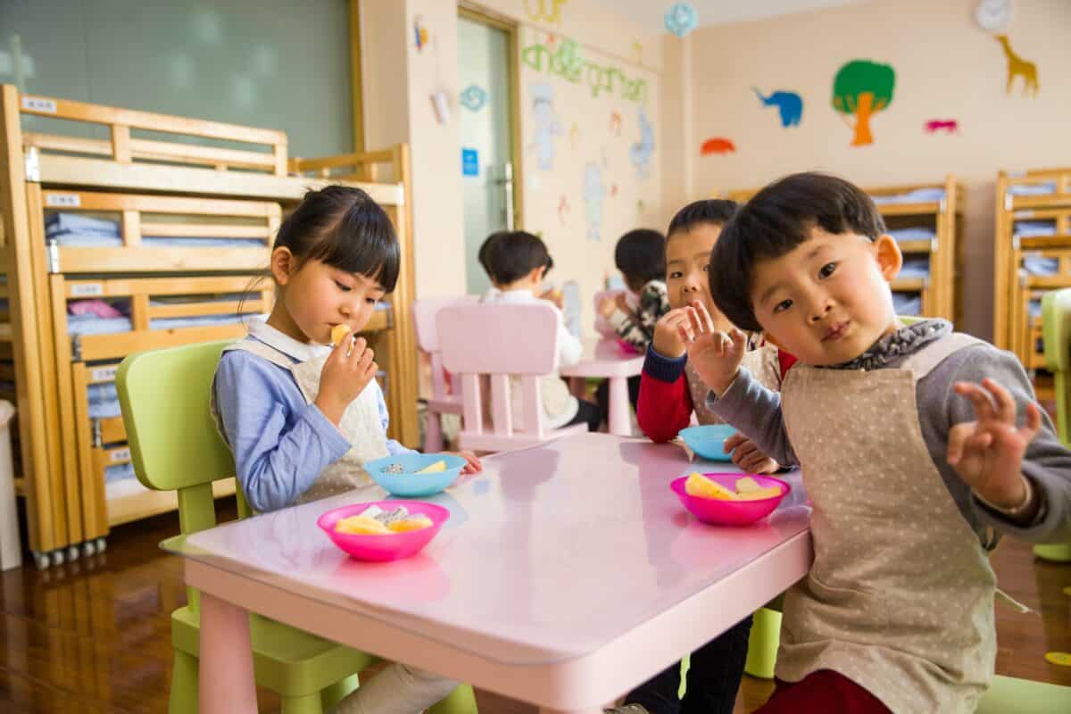 children at day care sitting at small table eating