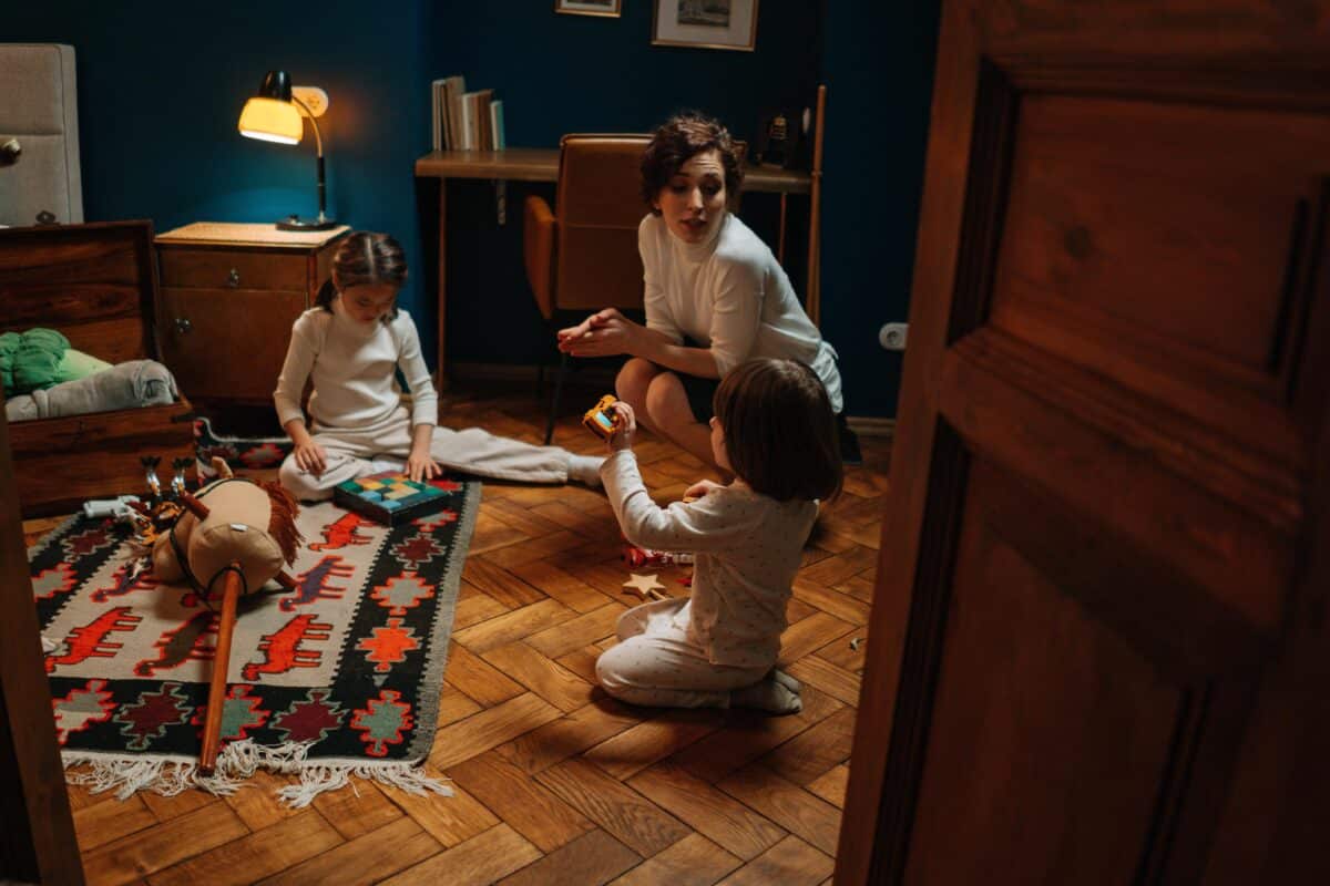 a nanny plays with two children while at home