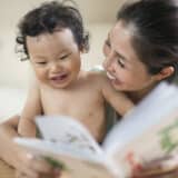 Best Read-Aloud Books For Babies - Asian woman reading book to smiling baby