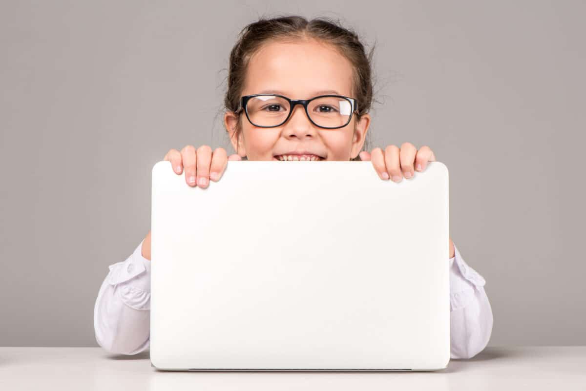 Little girl with blue light glasses looking over a computer screen 