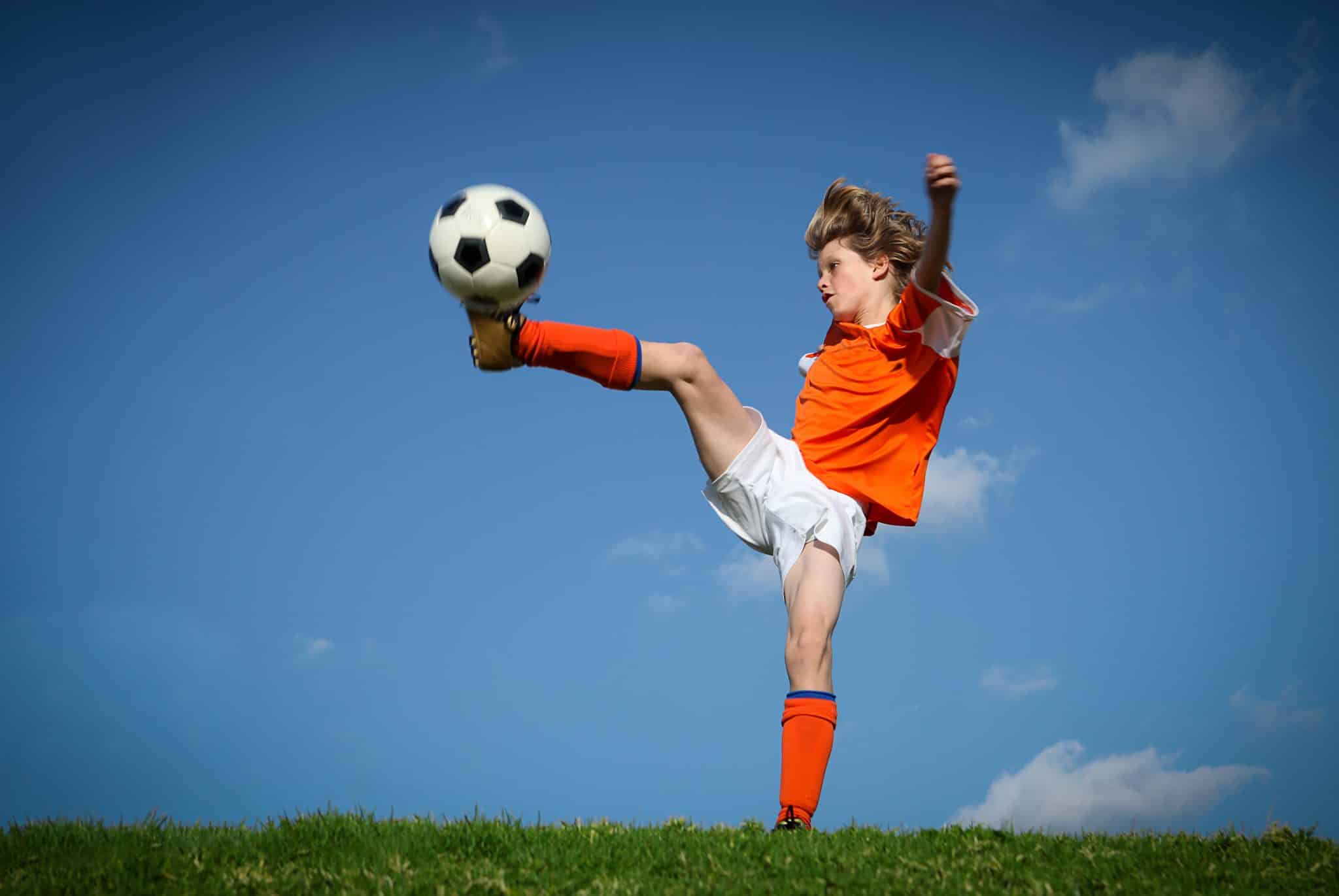 athletic child kicking a soccer ball in a field