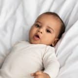 baby lying on white bed