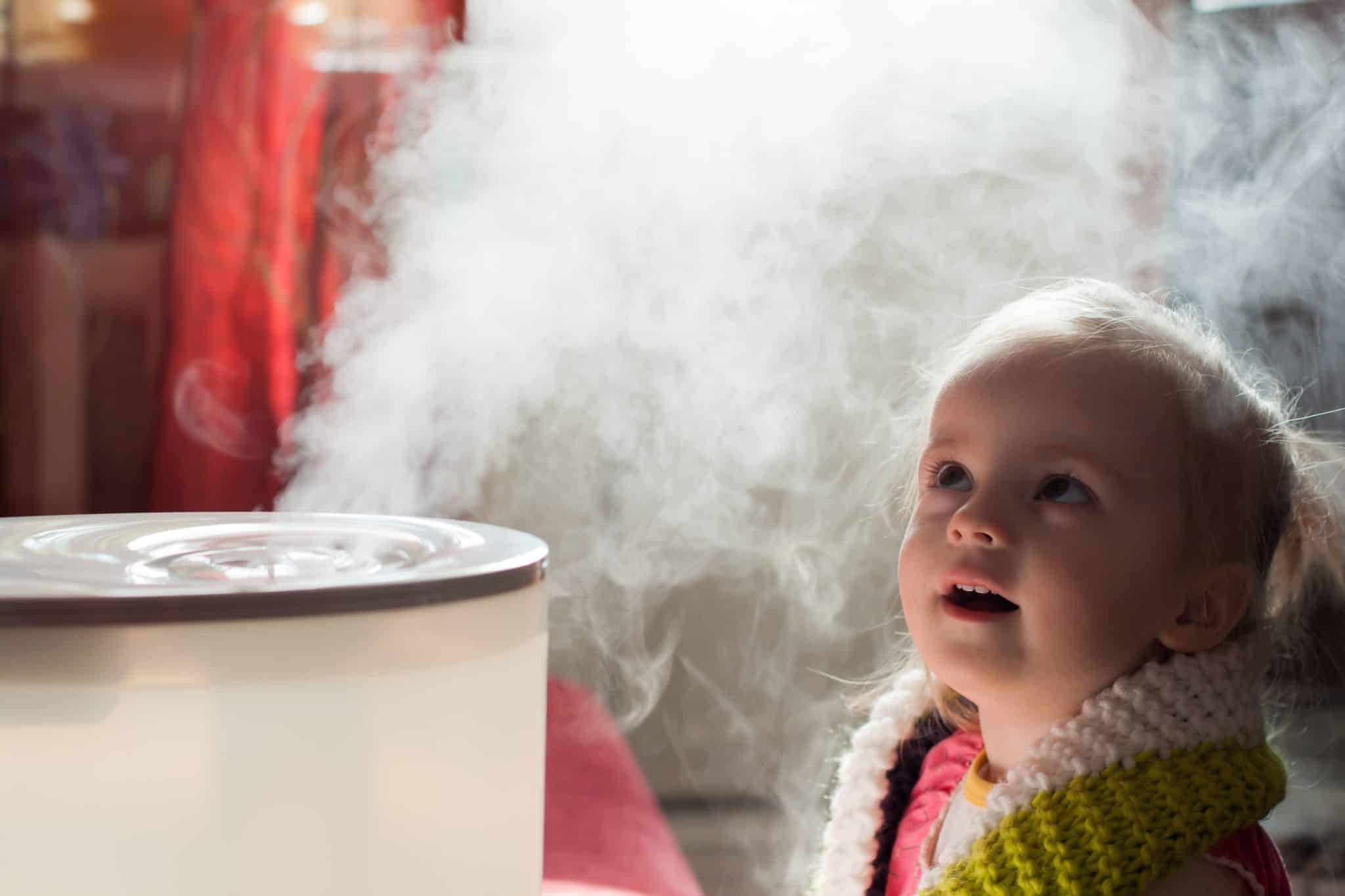 Little girl breathing in the mist from a humidifier